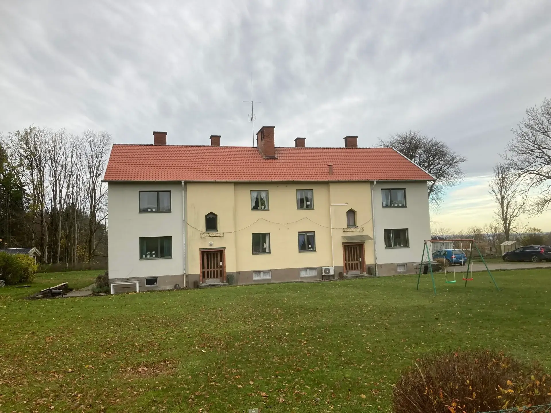 Medelplanagården, ein gelbes zweistöckiges Haus mit rotem Dach, an einem Herbsttag